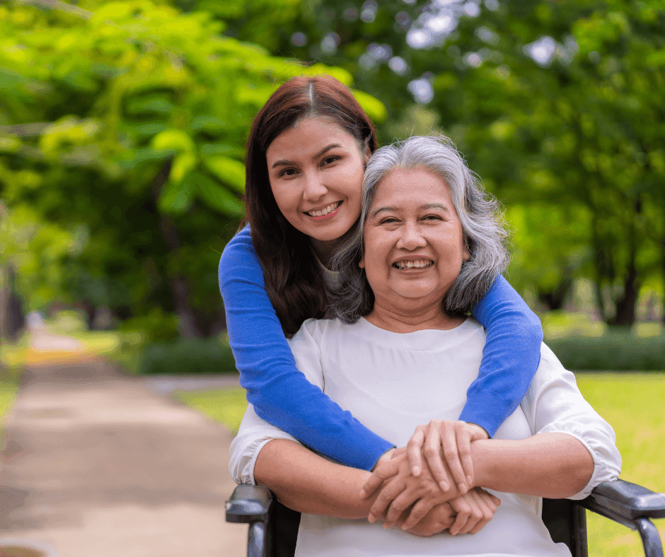 Daughter with arms round elderly mother in wheelchair.png